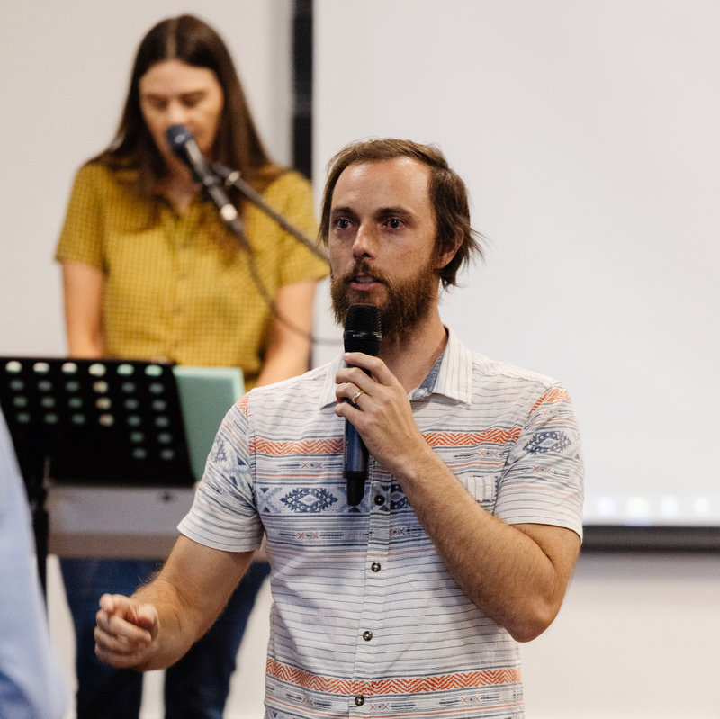 Josh Wood preaching with musician in the background